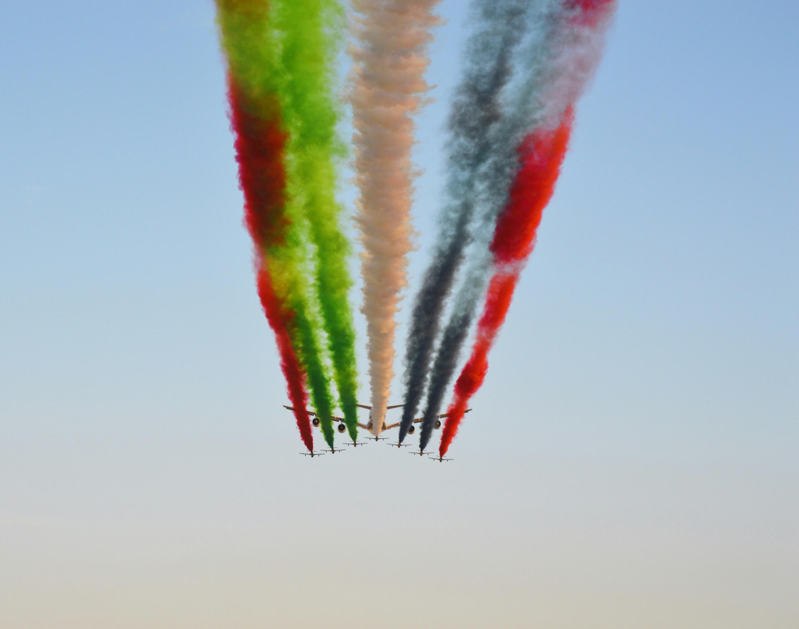 Aircraft performing UAE national day aerial show in red green white black flag colors symbolizing how UAE got independence
