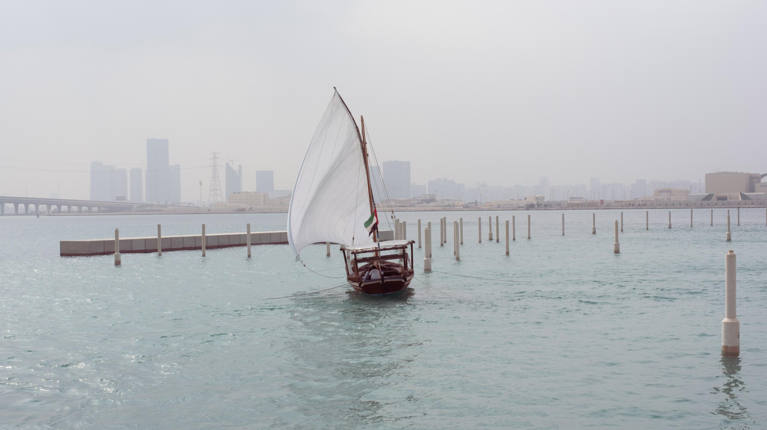 Traditional Arabian dhow sailing in Dubai Creek, symbolizing the maritime heritage of the Trucial States era