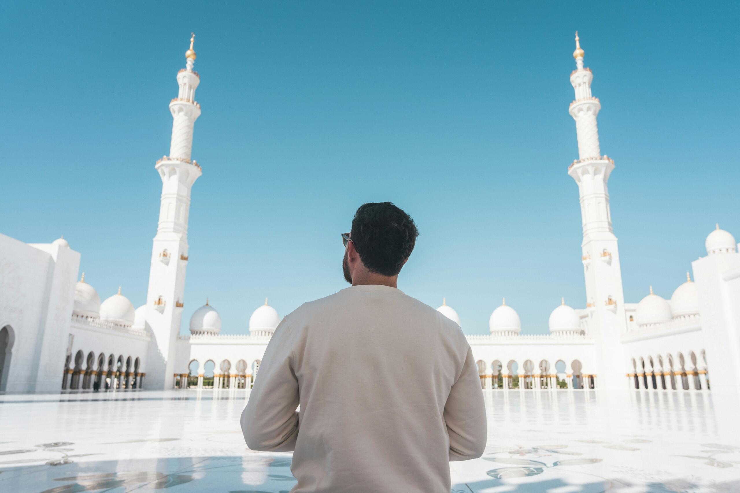 A Muslim man standing in the courtyard of a mosque reflecting on the Islamic New Year