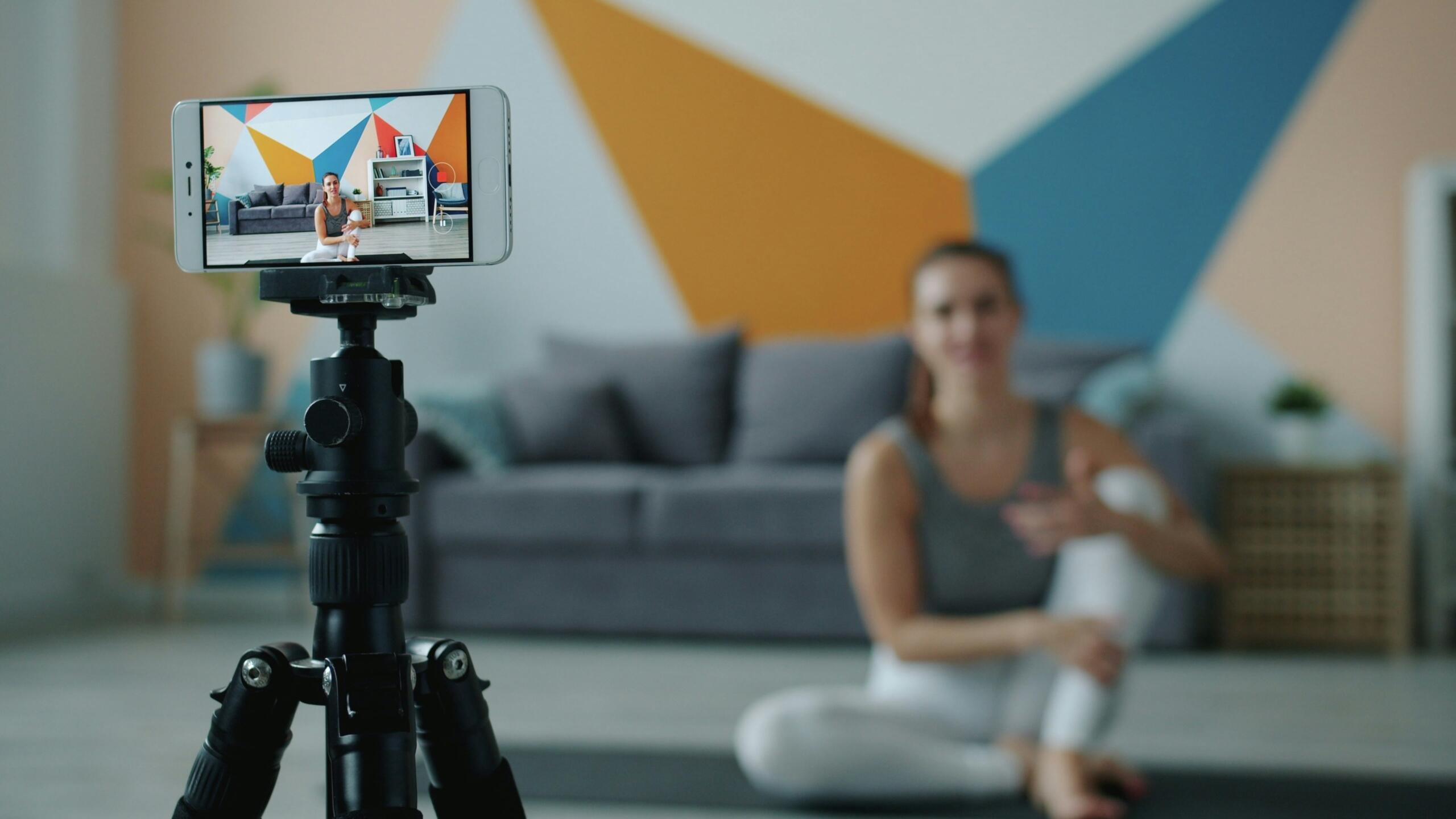 Person duke regjistruar video fitnesi me telefon mbi tripod — trajnimi personal online dhe çmimi më i arritshëm falë internetit.