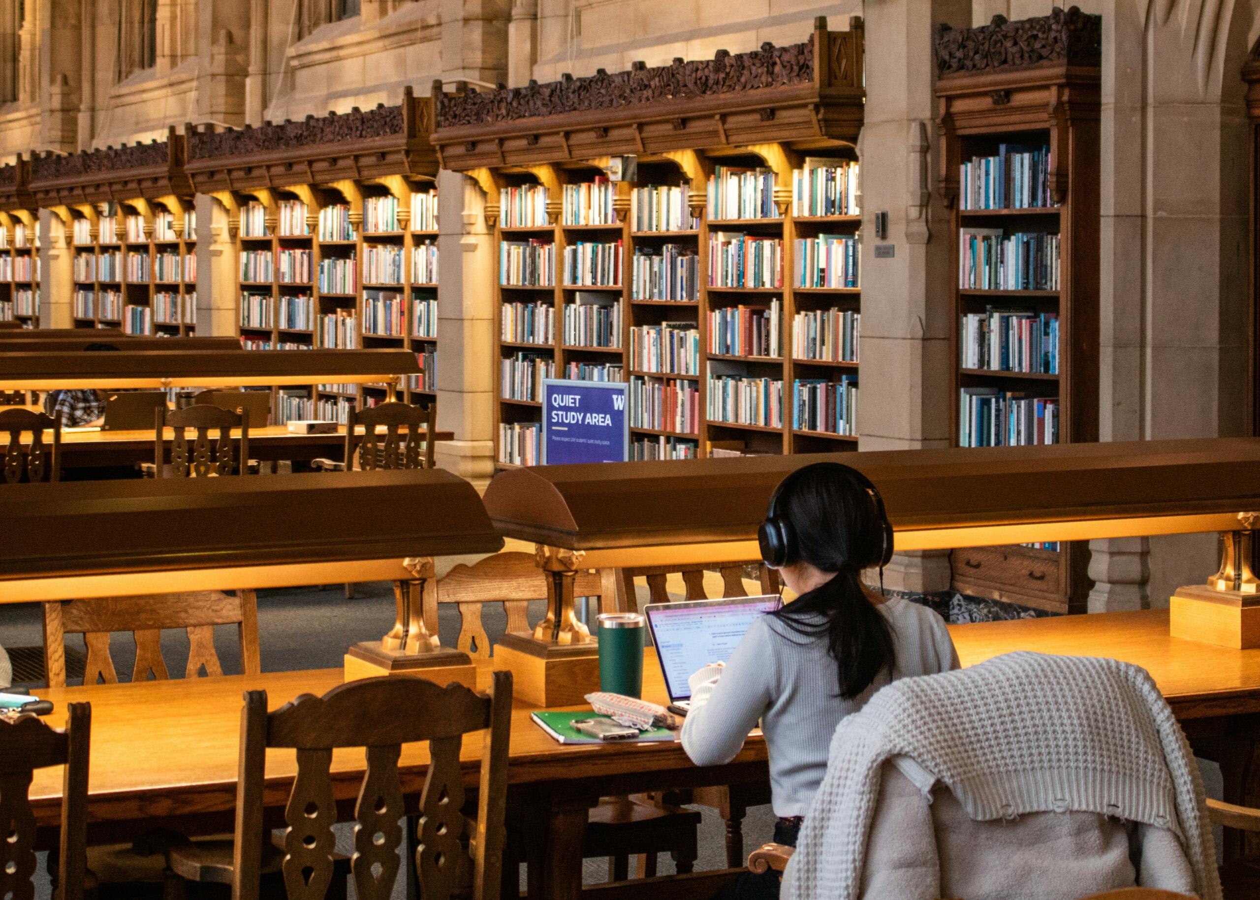 Student duke studiuar në një bibliotekë të madhe — tre nivele fokusimi dhe qasje realiste ndaj përqendrimit.