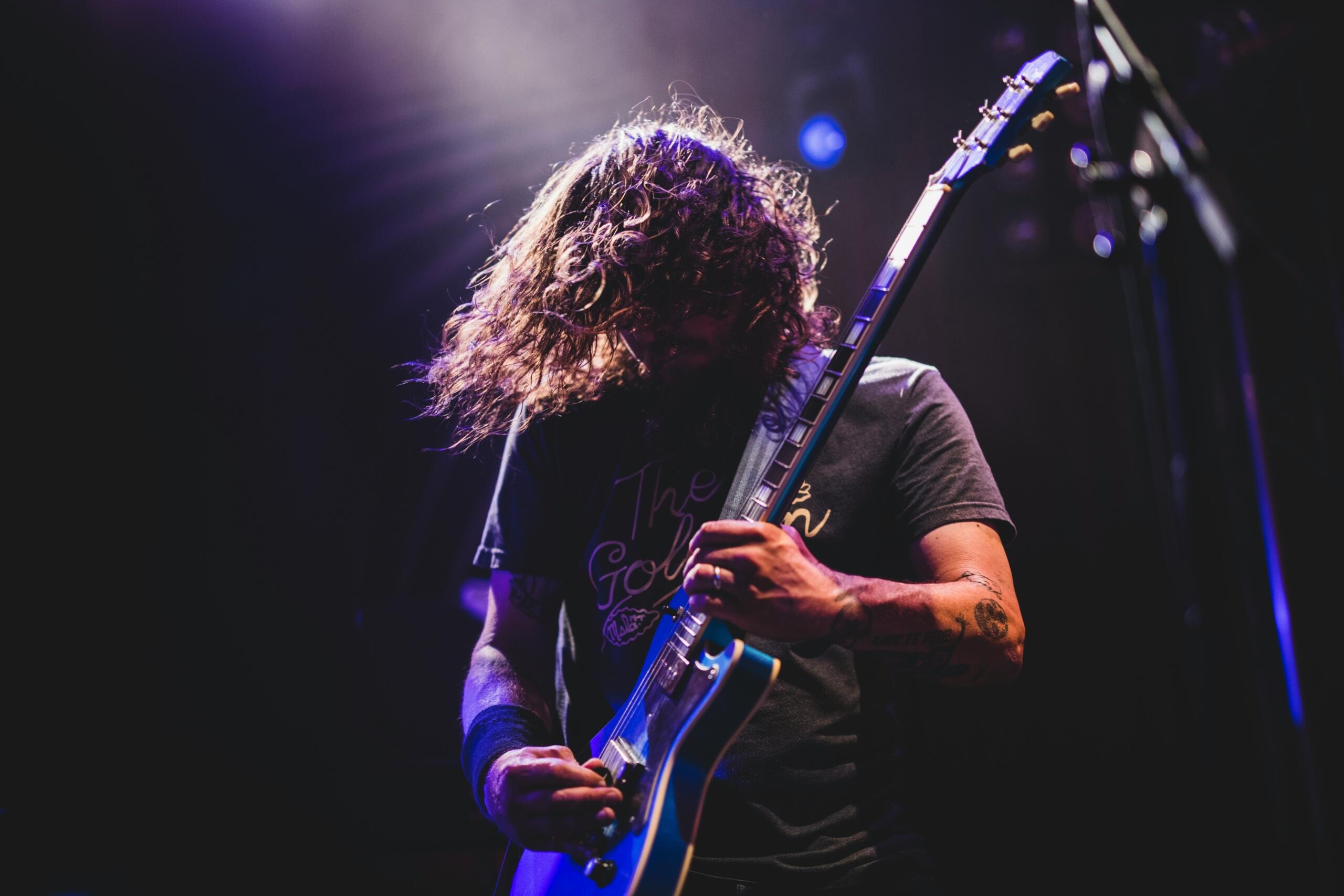 Burrë duke luajtur kitarë elektrike — kitaristët më të famshëm dhe legjendat që frymëzojnë brezat.