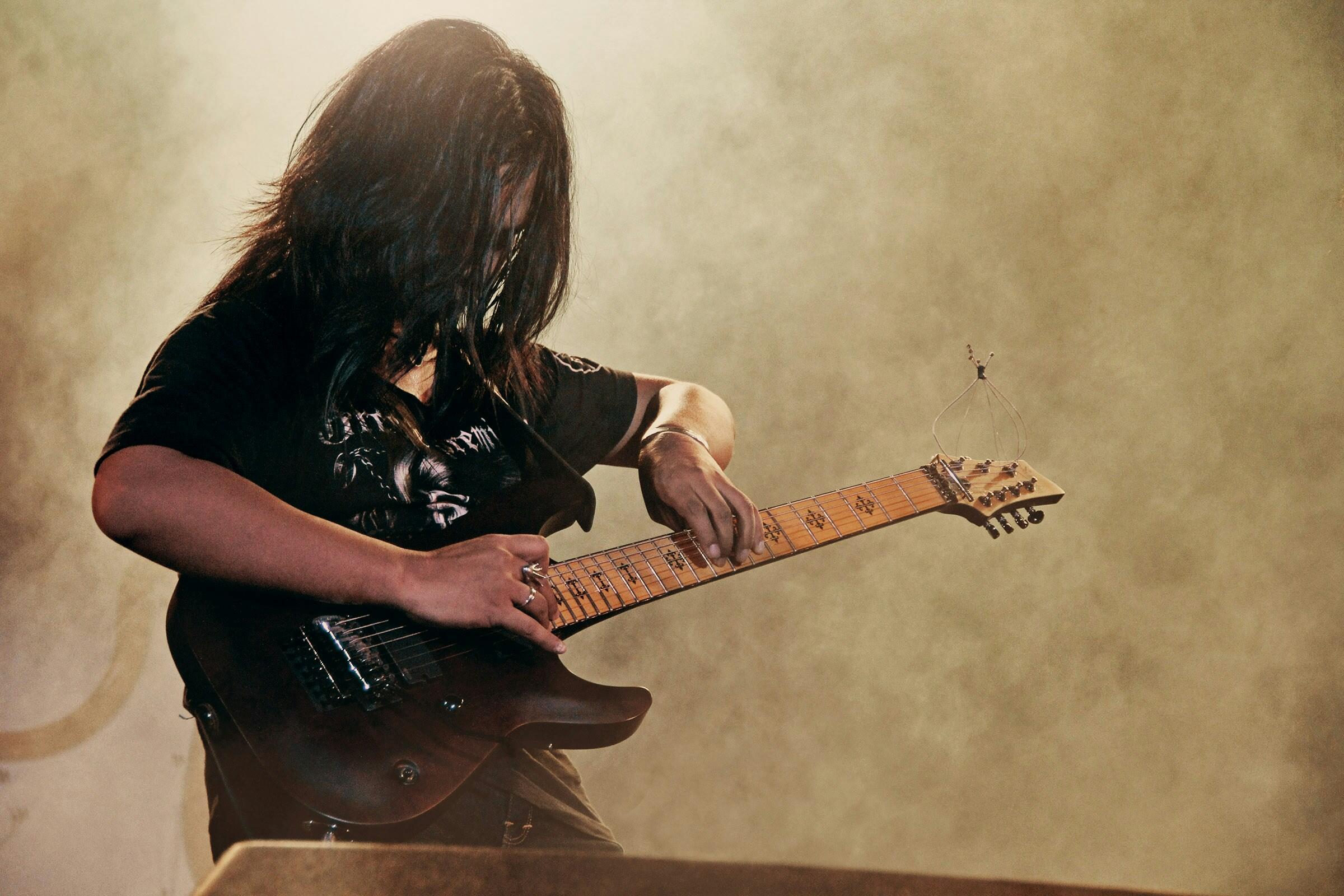 Person duke mbajtur kitarë elektrike të zezë — si të bëhesh kitarist profesionist.