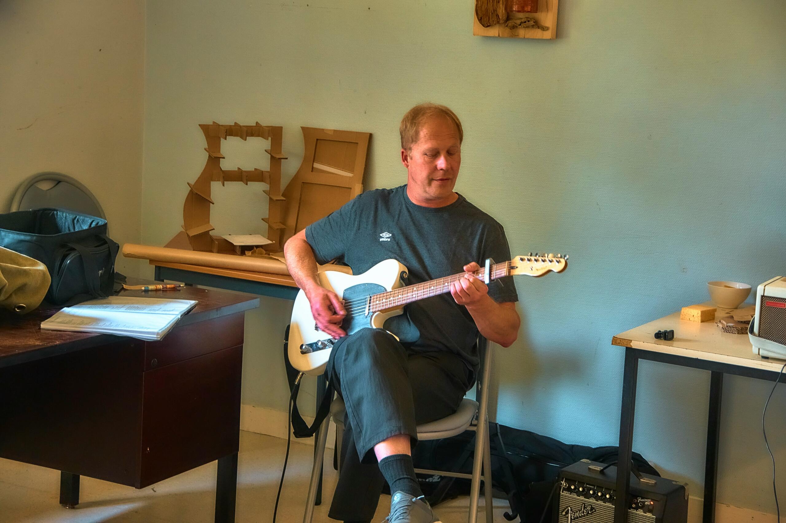 Person duke luajtur kitarë elektrike të bardhë — sa paguhet një mësues kitare dhe çfarë e ndikon çmimin.