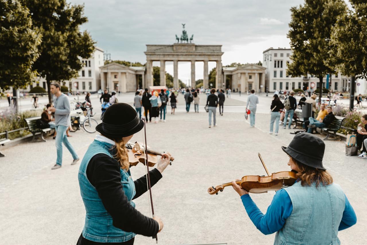 Dos personas tocando el violin en lugar público