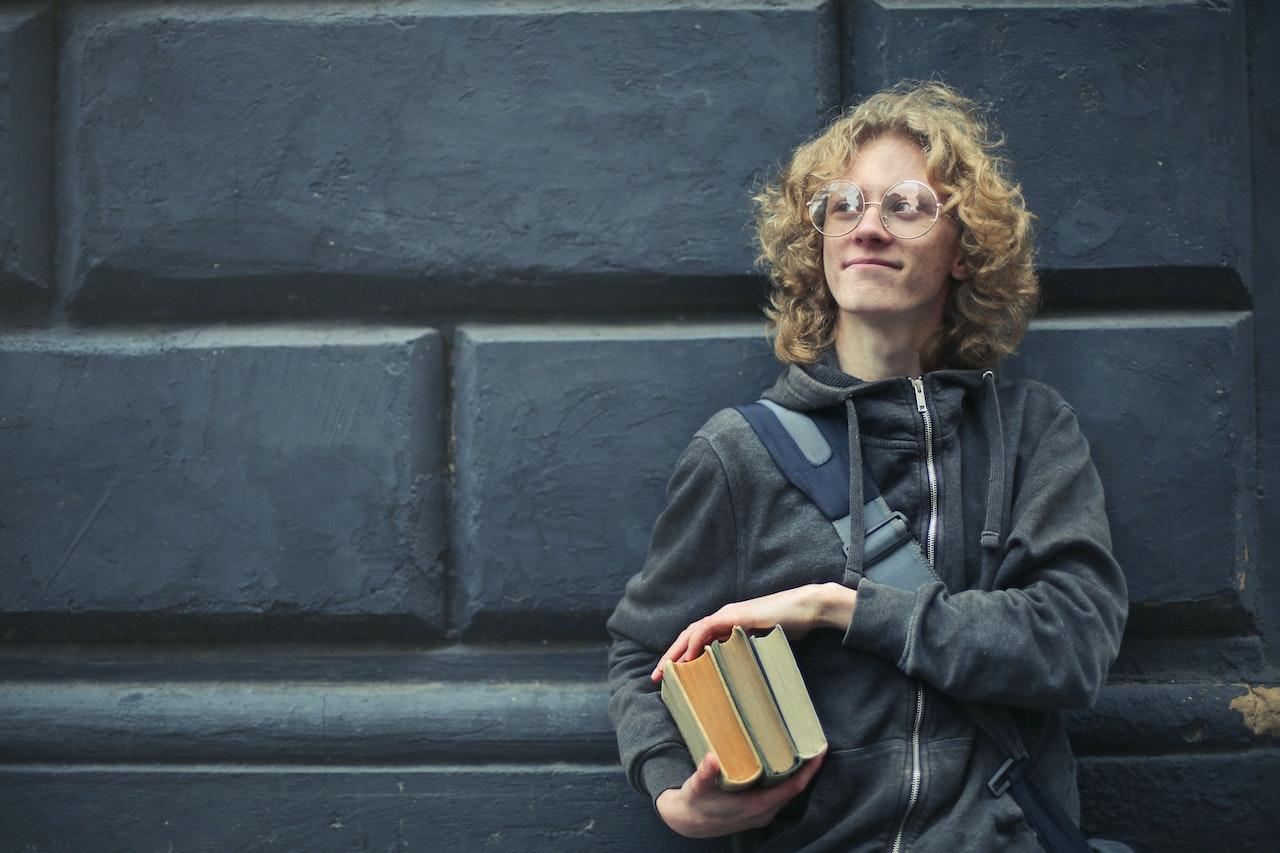 Joven sosteniendo libros.