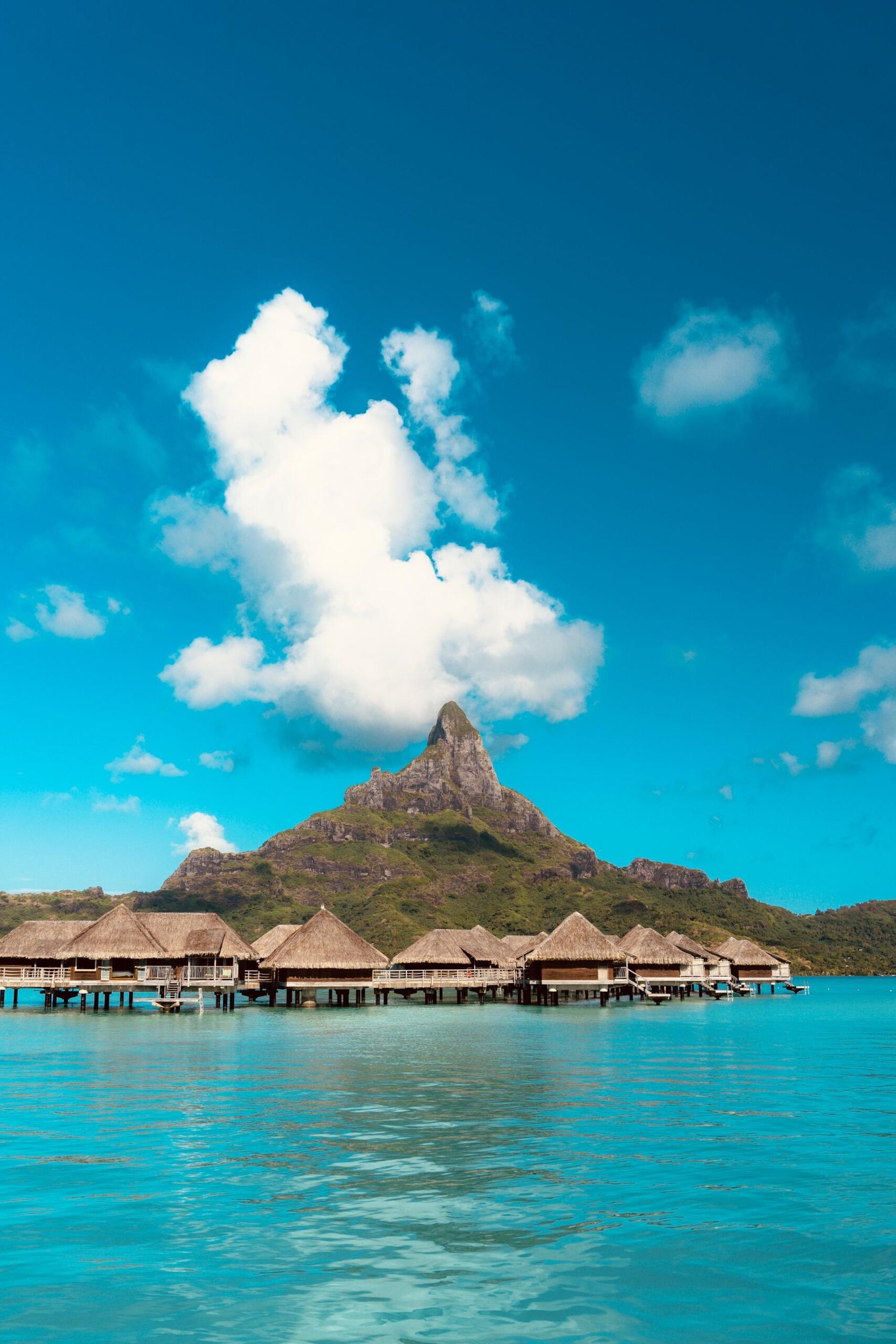 Bora-Bora, Polinesia Francesa, bungalows sobre el agua y montañas, foto por Adrien Daurenjou en Pexels.