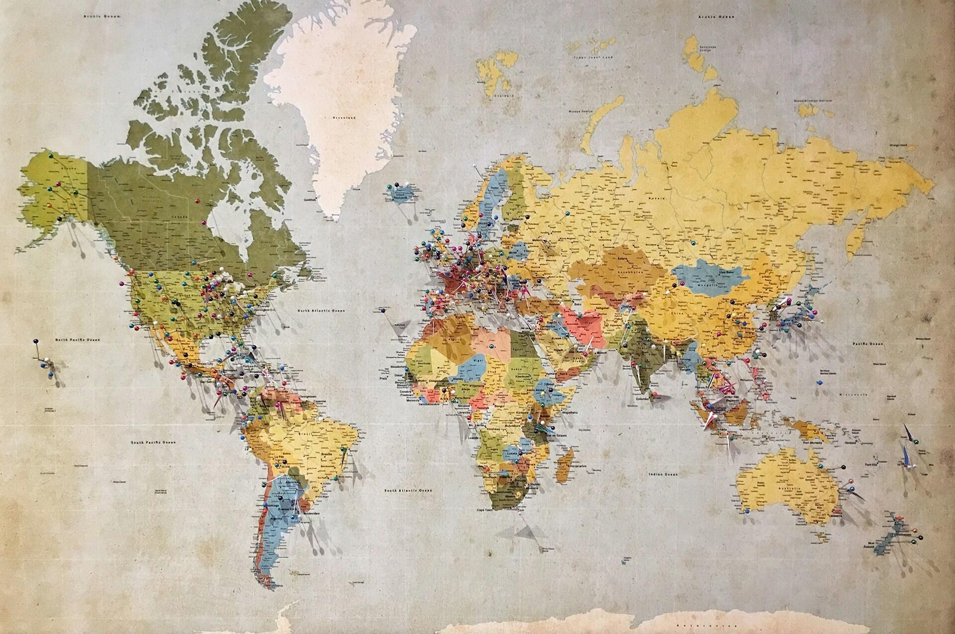 Mapa mundial con pines marcando destinos globales, foto por Andrew Stutesman en Unsplash.