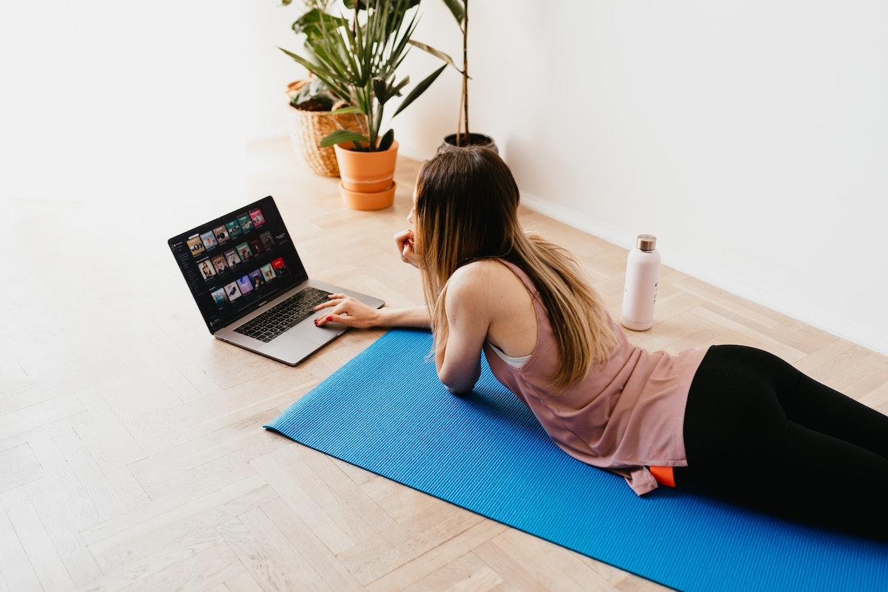 Mujer junto a la computadora haciendo pilates.