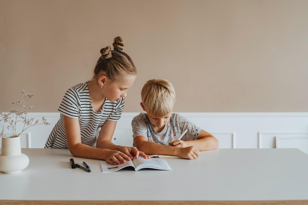 Hermanos en la mesa con un libro