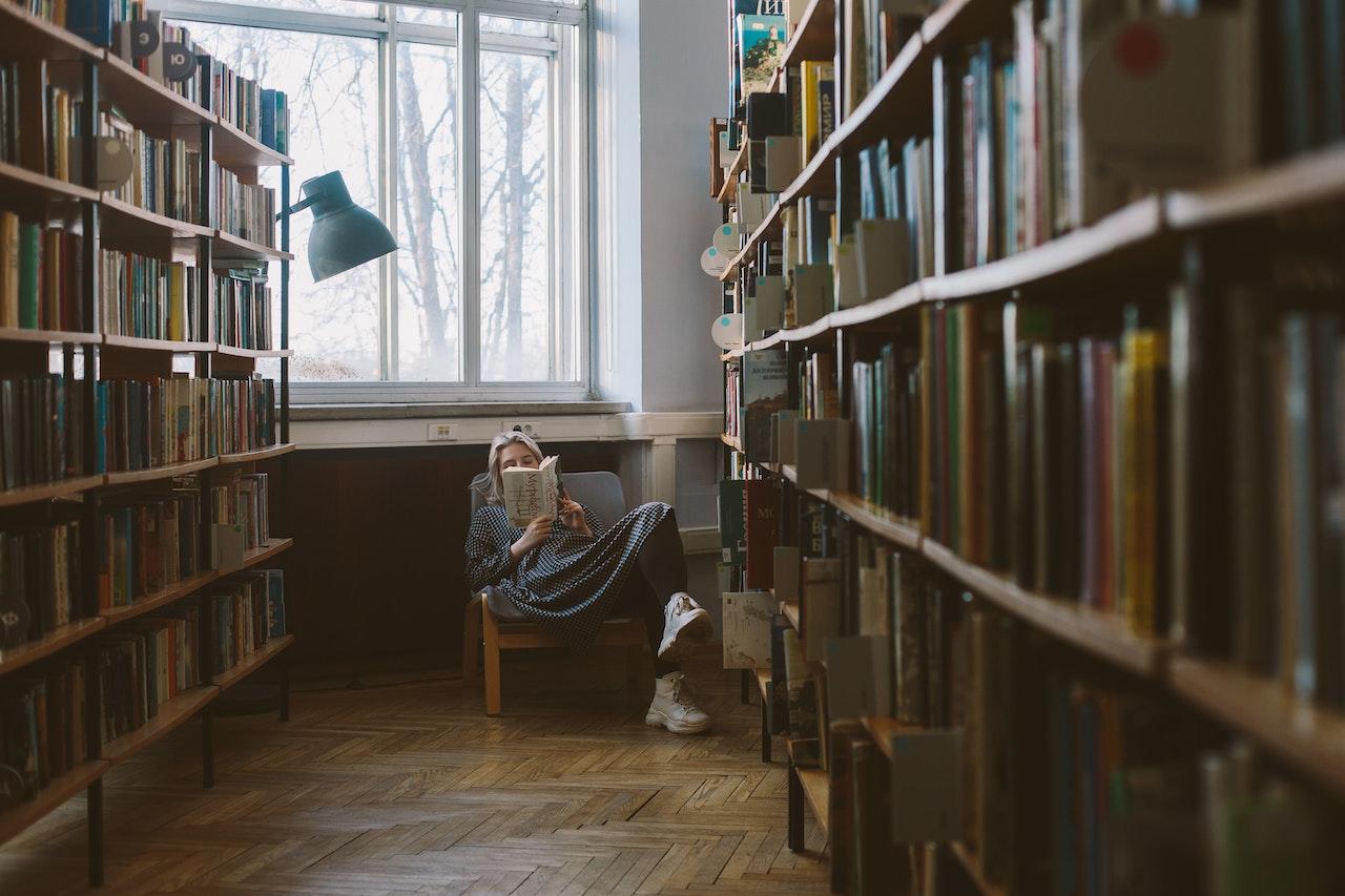 Mujer leyendo sentada en una silla, en una biblioteca