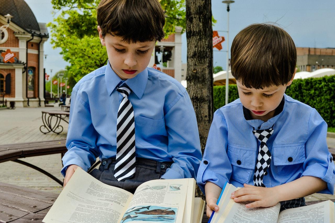 Niños con camisa y corbata leyendo.