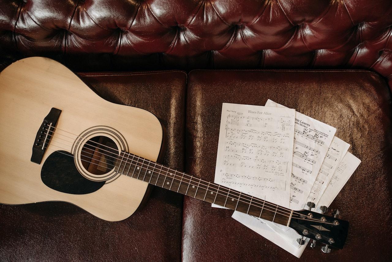 Guitarra y partituras sobre el sillón