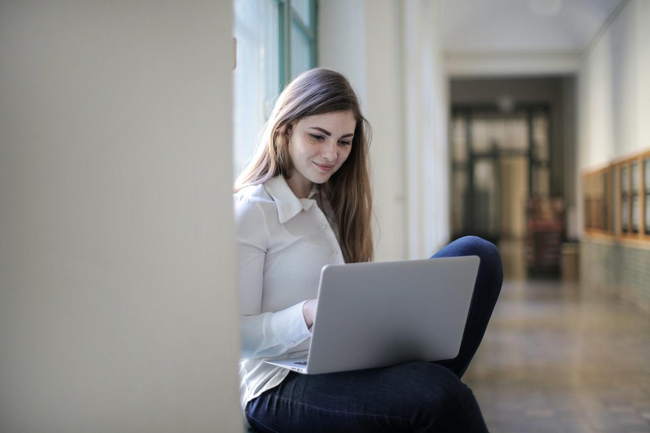 Mujer con la computadora en el pasillo.