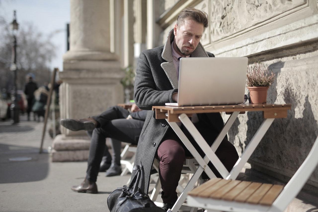 Hombre sentado al aire libre trabajando con la computadora.