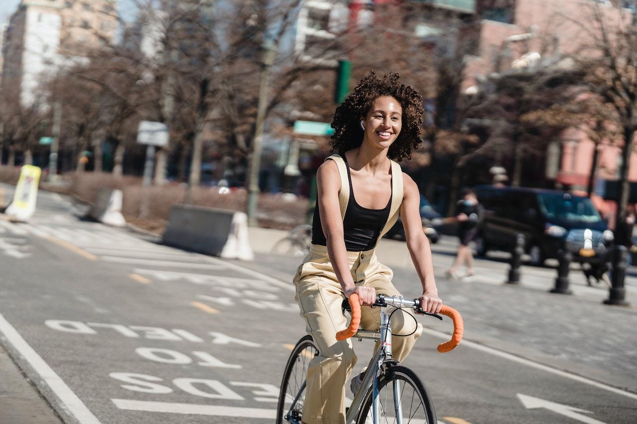 Mujer andando en bicicleta con auriculares puestos.