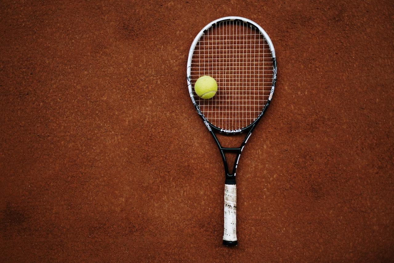 Raqueta y pelota sobre cancha de tenis de polvo de ladrillo. 