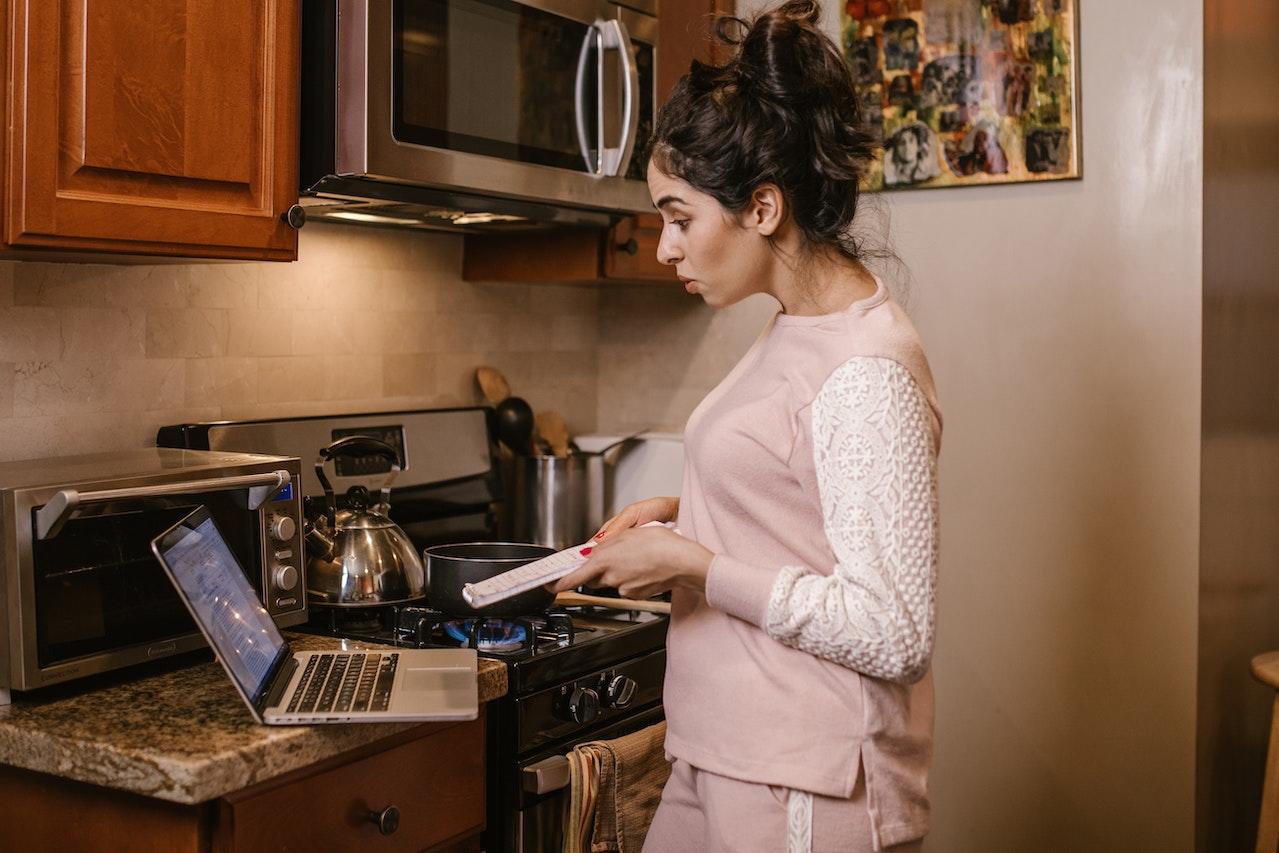 Mujer con la computadora en la cocina.