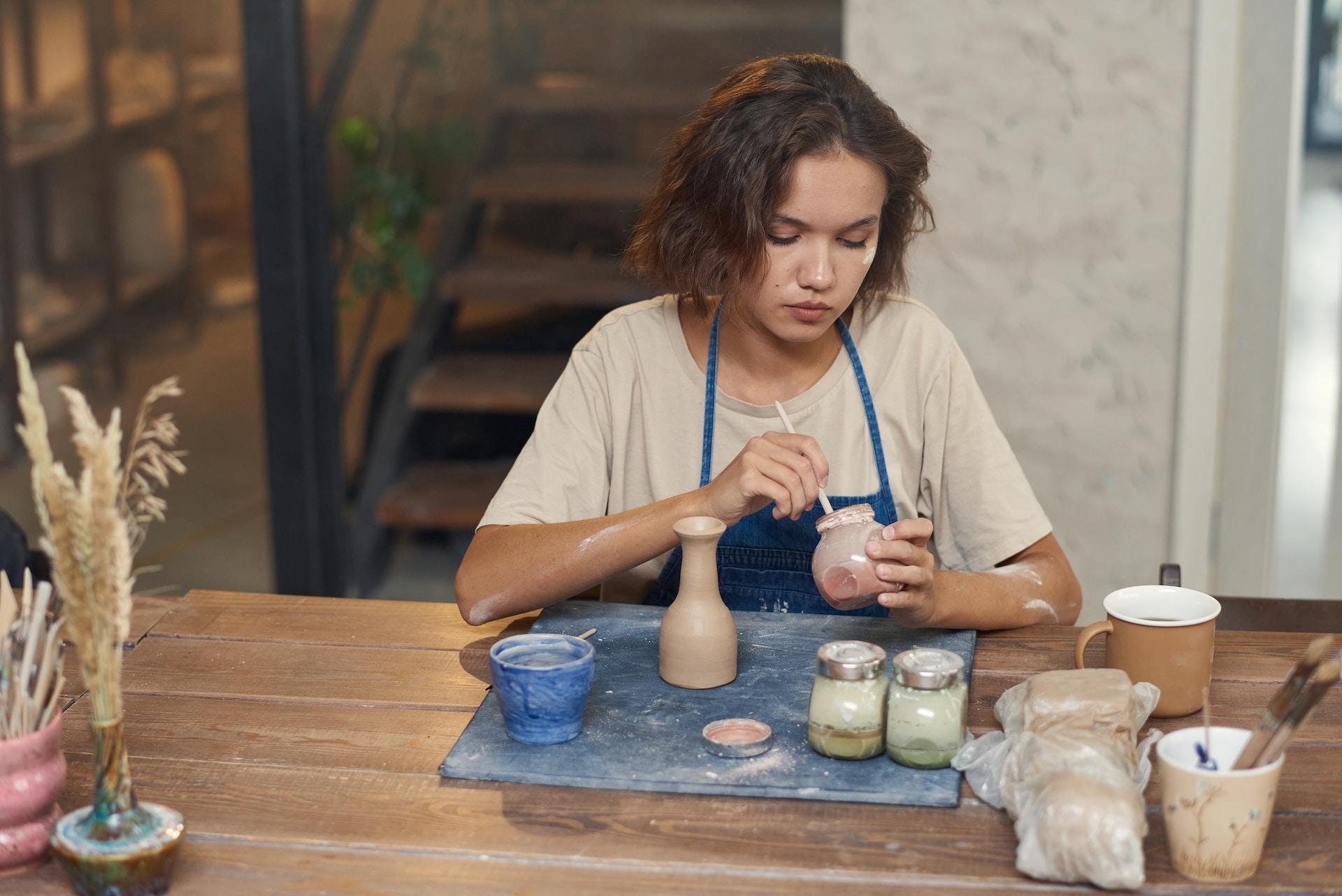Joven pintando piezas de cerámica.