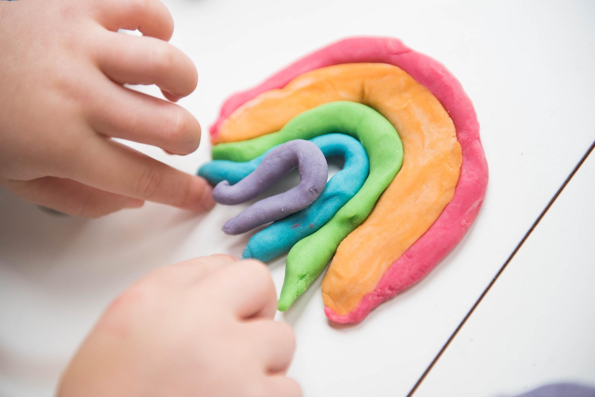 Manos jugando con arcilla de colores.