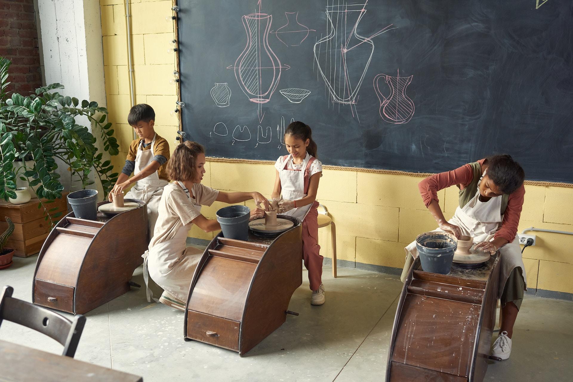 Niños en una clase de cerámica junto a su profesora.