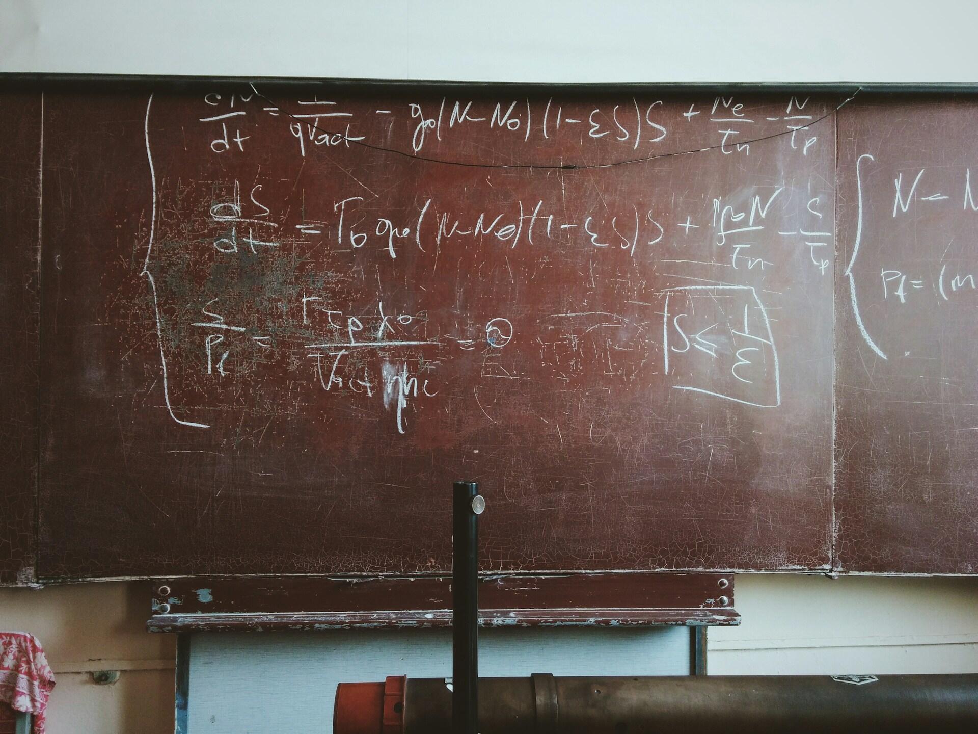 Pizarrón de un aula con ecuaciones de física y cálculo avanzado escrito con tiza, representando el análisis matemático, fotógrafo: Roman Mager.