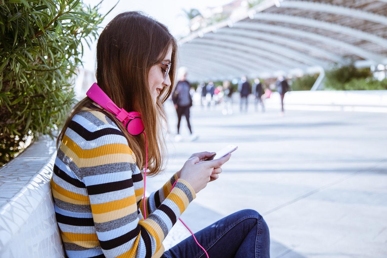 Mujer con el teléfono móvil y auriculares.