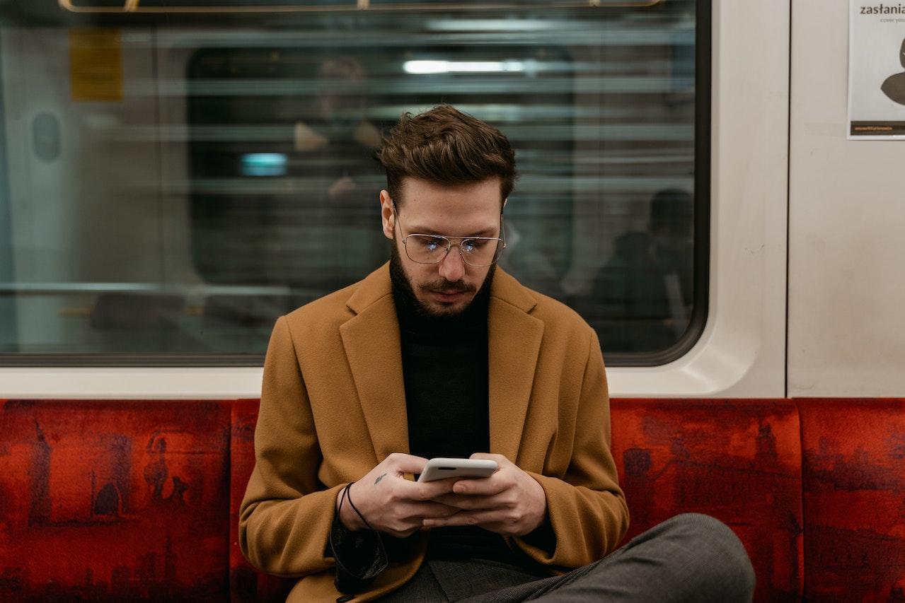 Joven con el celular viajando en subte. 