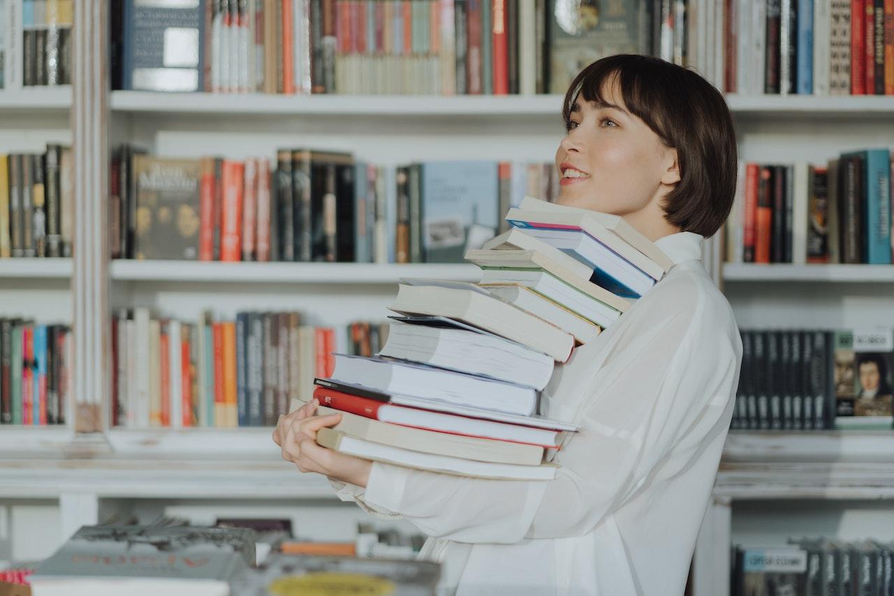 Mujer sosteniendo una pila de libros.