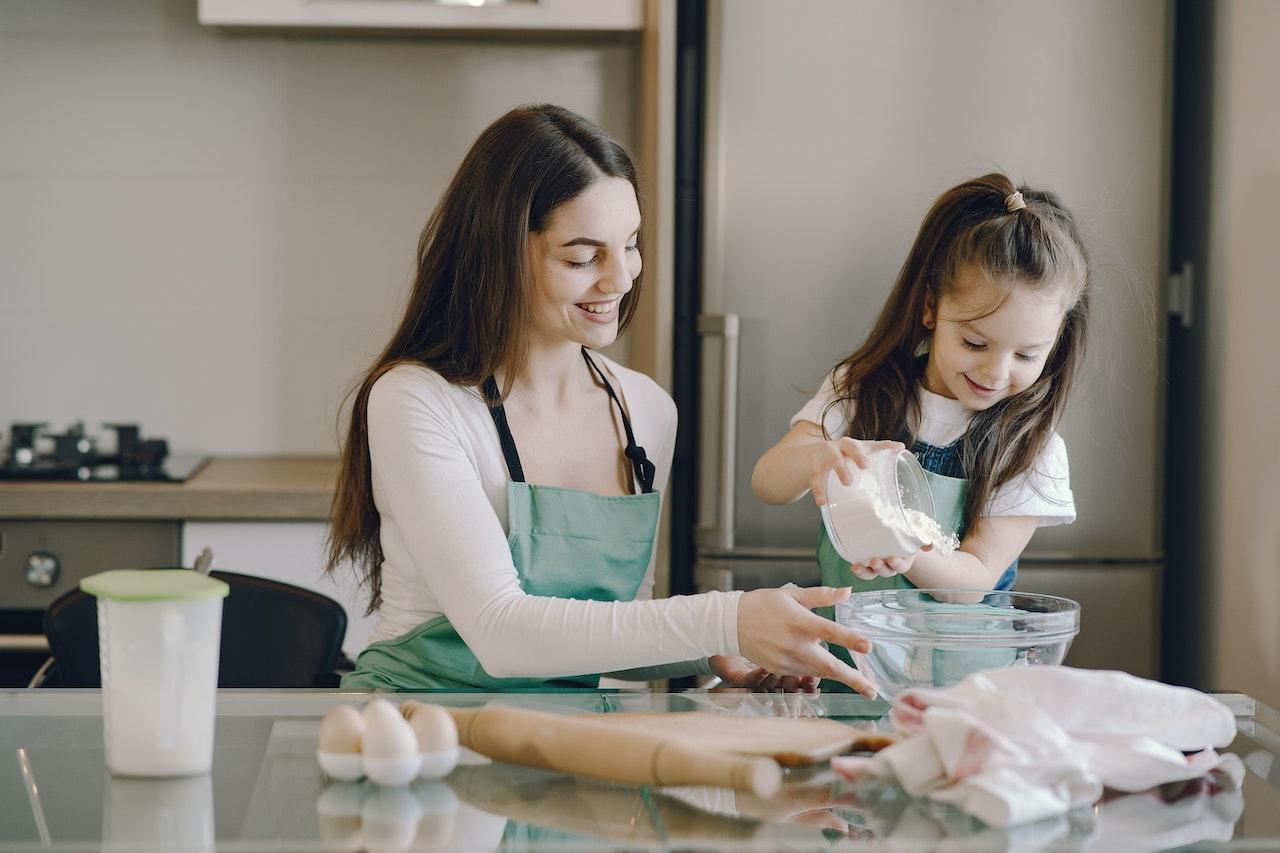 Mujer joven y niña cocinando en la cocina. 
