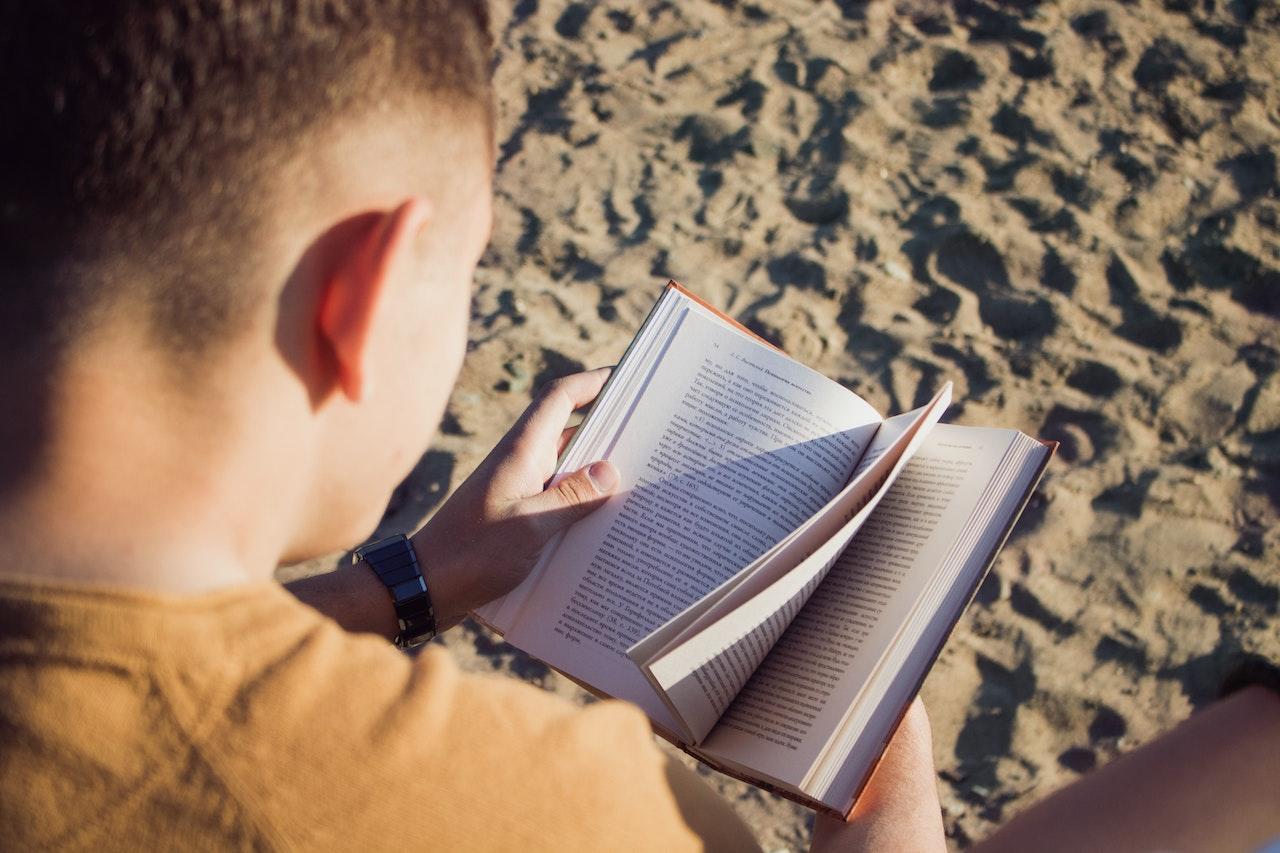 Muchacho leyendo en la arena. 