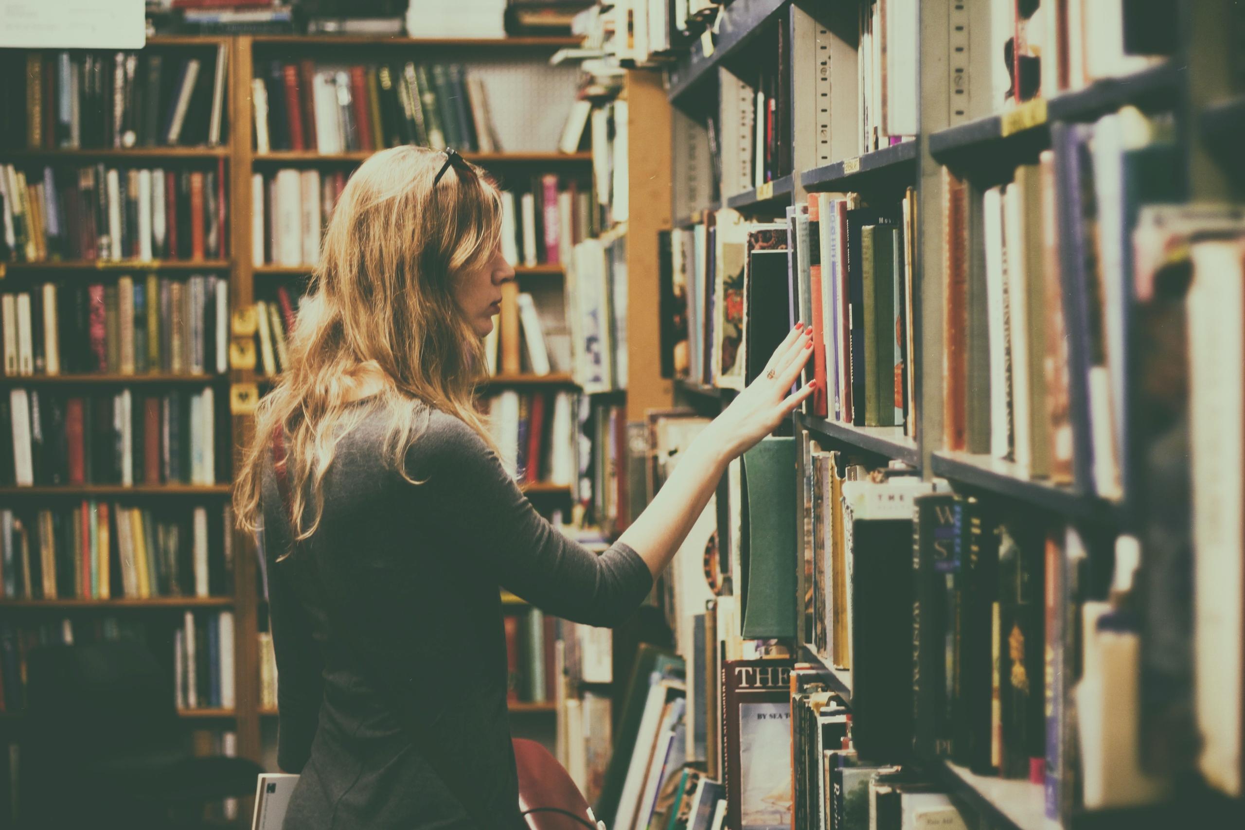 Mujer eligiendo libros en la biblioteca. 