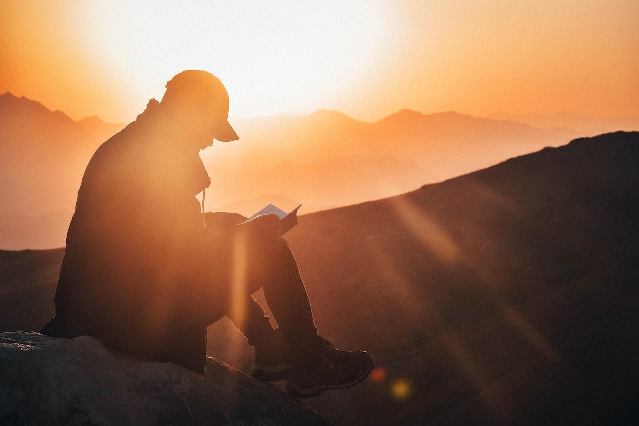 Hombre leyendo en la montaña al atardecer.
