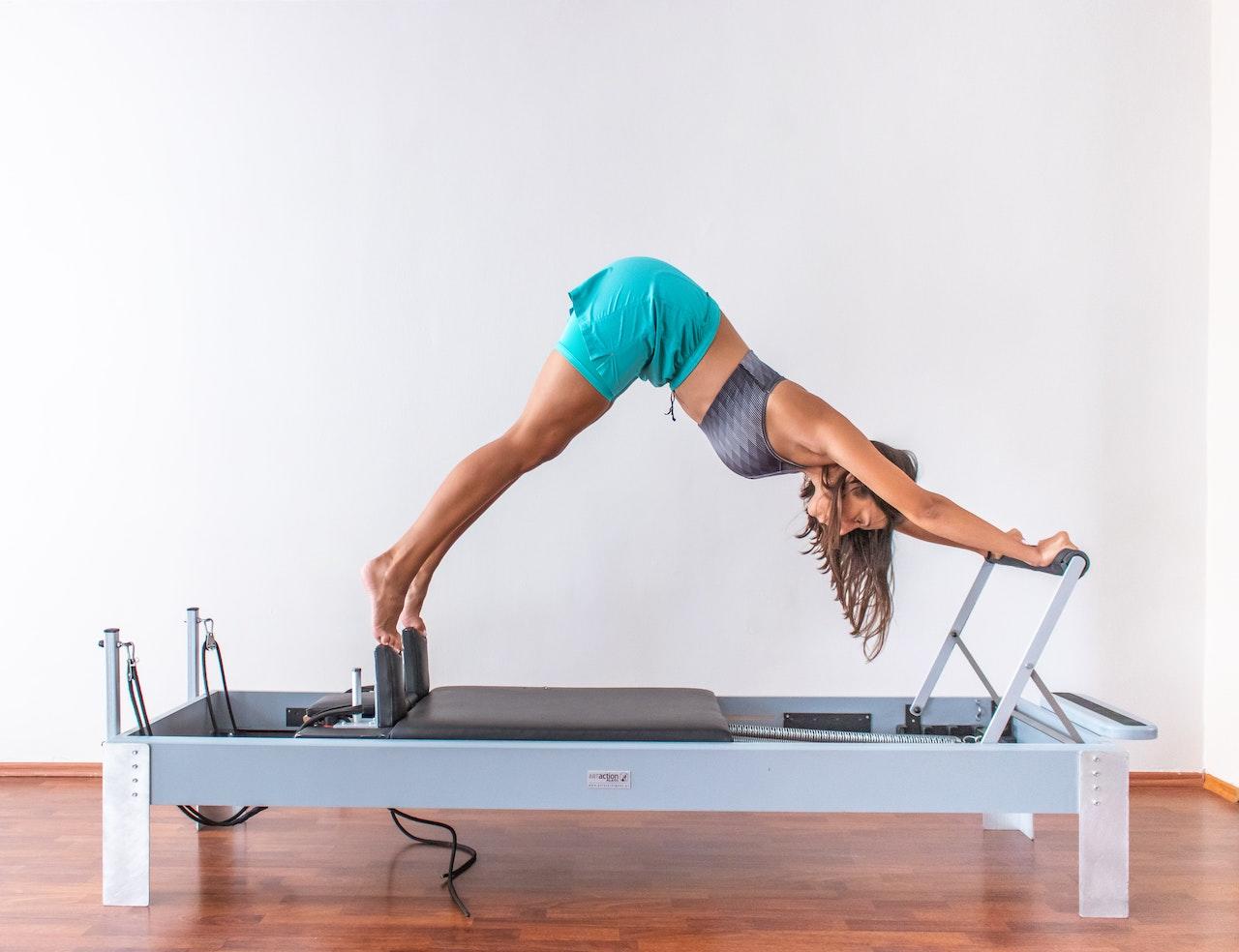 Mujer sobre camilla de pilates reformer
