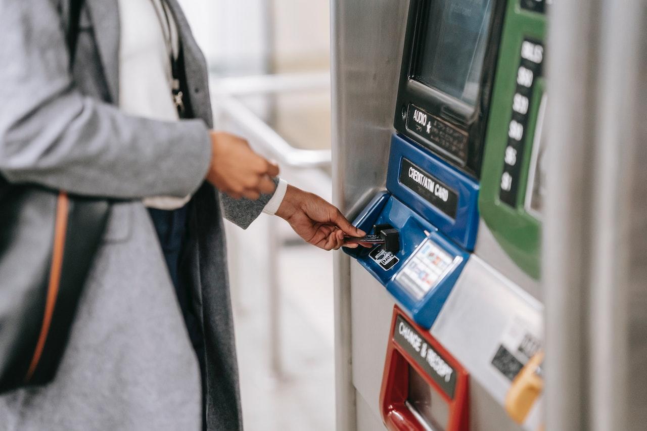 Mujer insertando tarjeta de débito en un cajero automático.