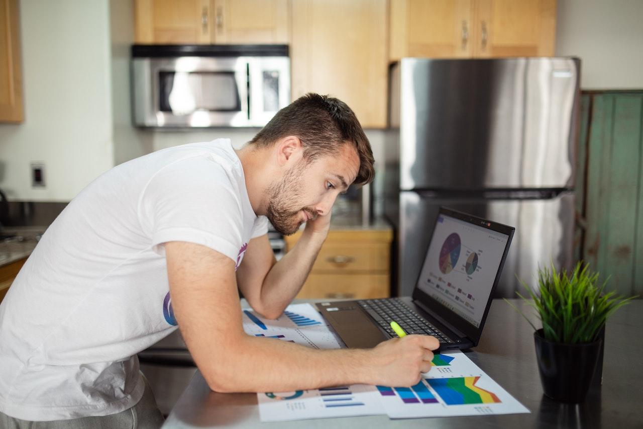 Hombre trabajando con gráficos en la cocina.