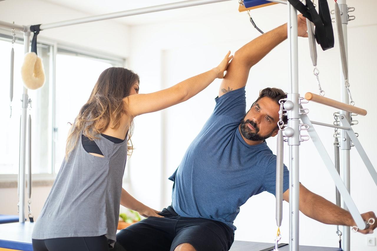 Alumno y profesora de gym, estirando.