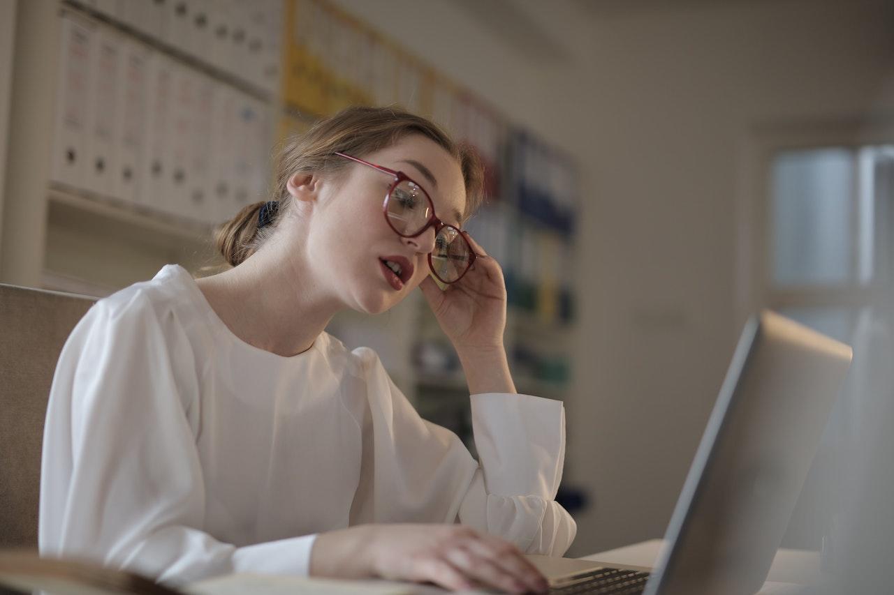 Mujer frustrada frente a la computadora con una taza de café.