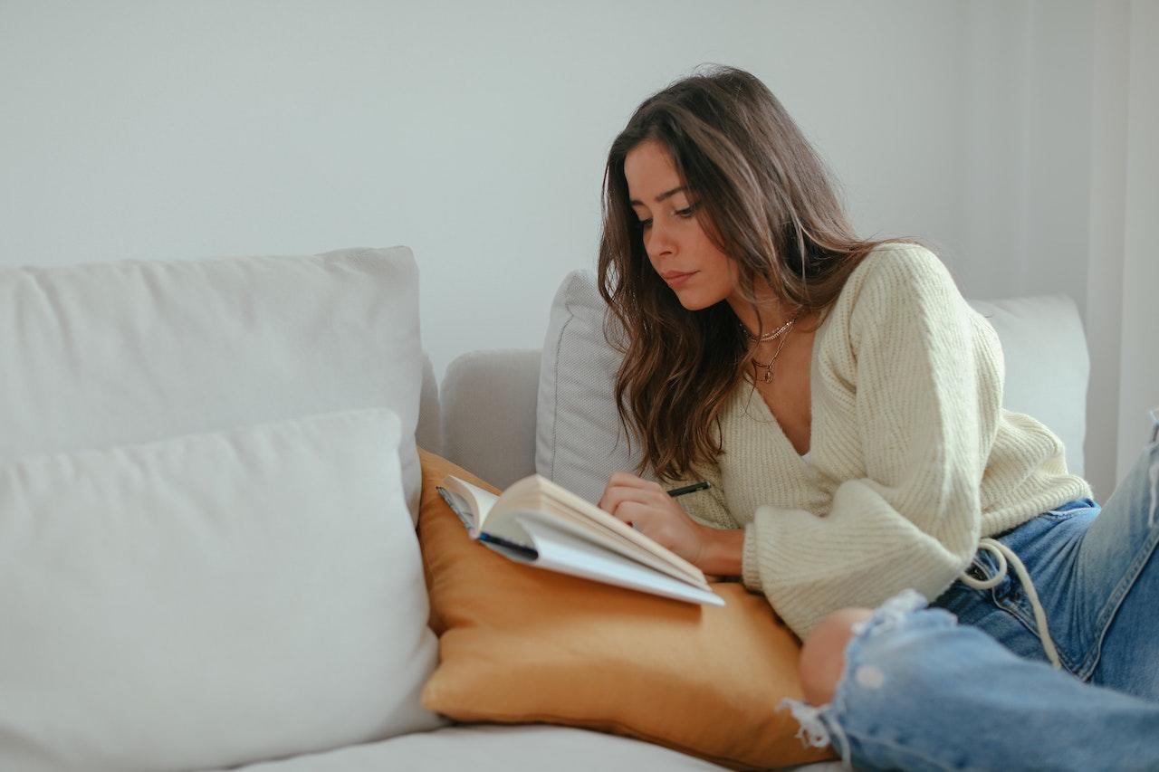 Mujer joven leyendo sobre la cama.