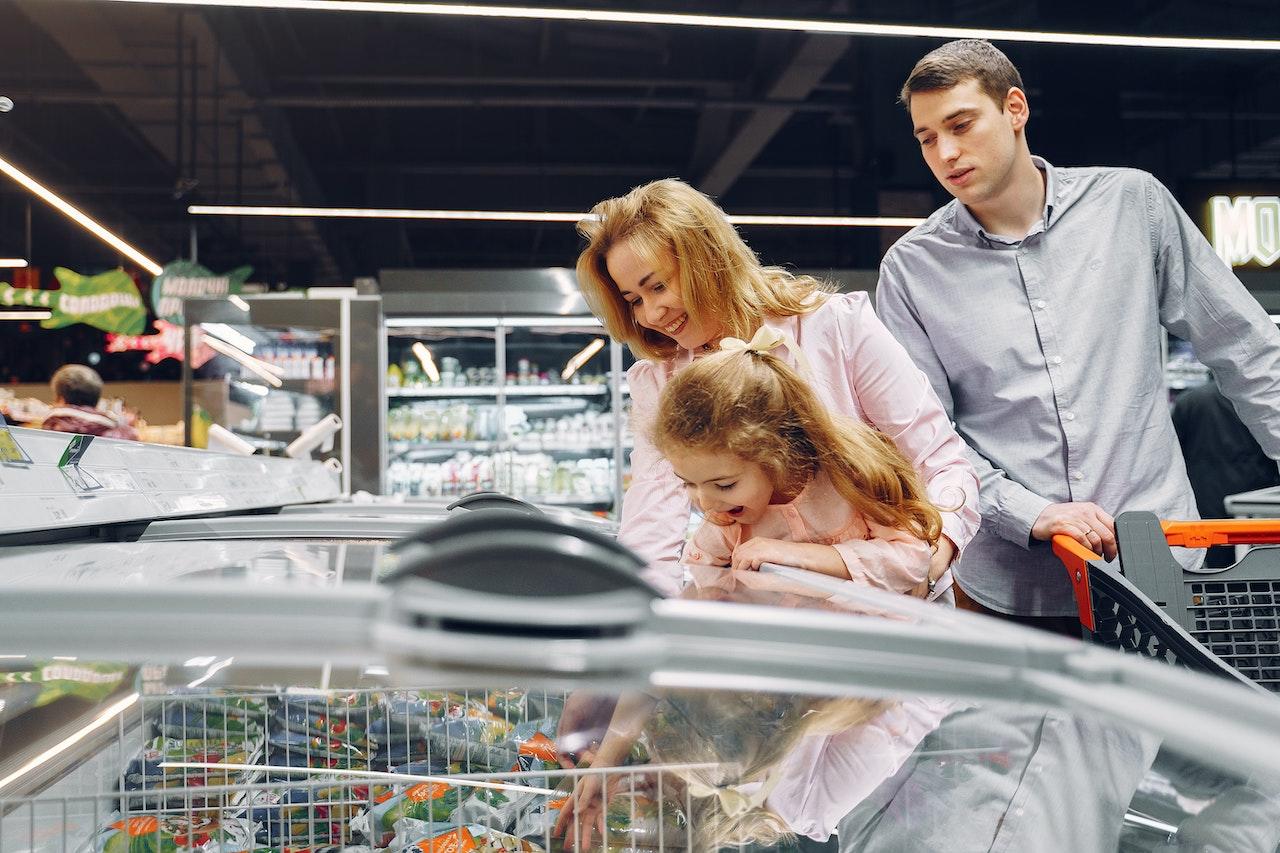 Madre padre e hija, haciendo las compras en el supermercado.