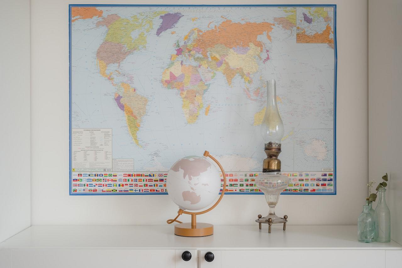 Pequeño globo terráqueo delante de un mapa planisferio.