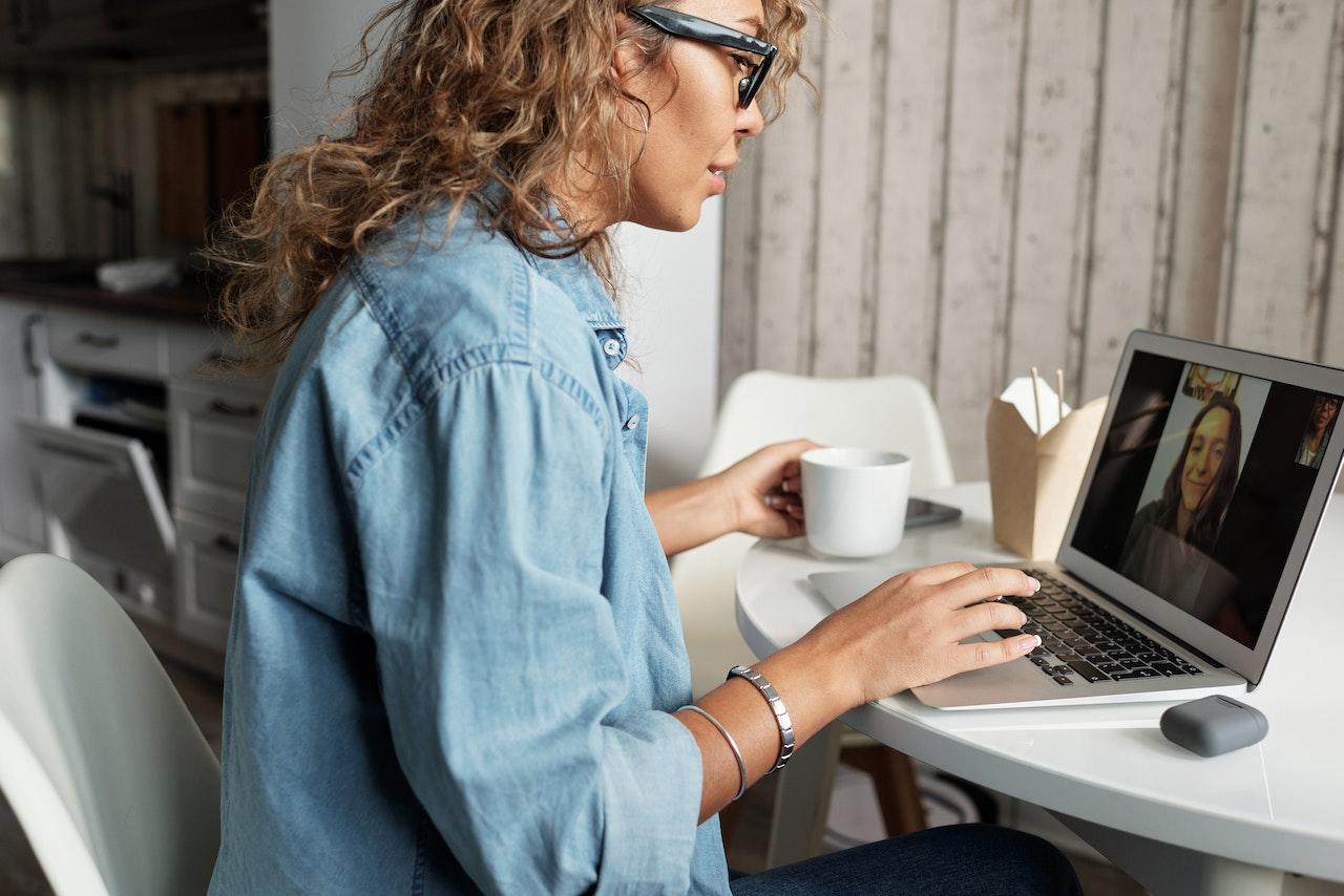 Mujer sentada haciendo una videollamada desde la computadora.