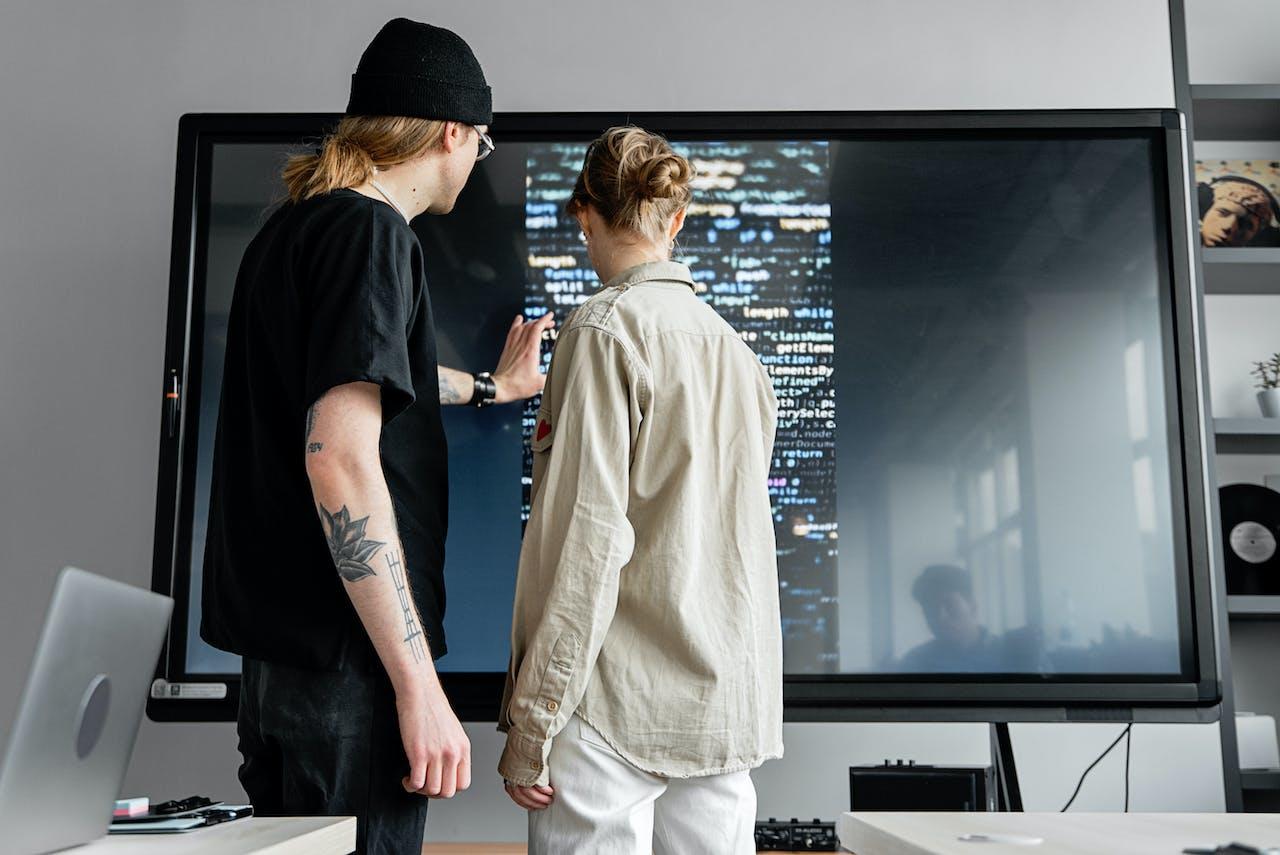 Personas mirando una pantalla con código.