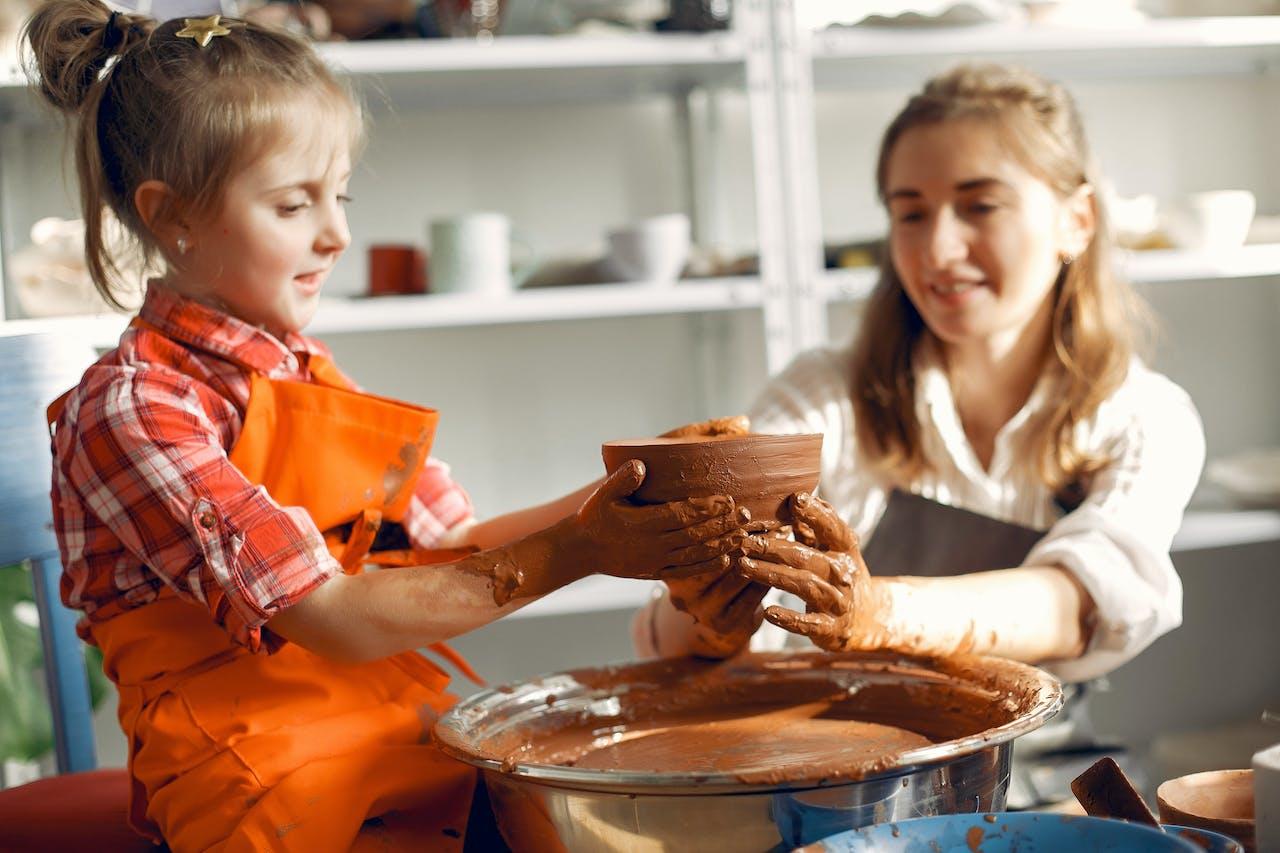 Adulta y niña trabajando con cerámica y torno.