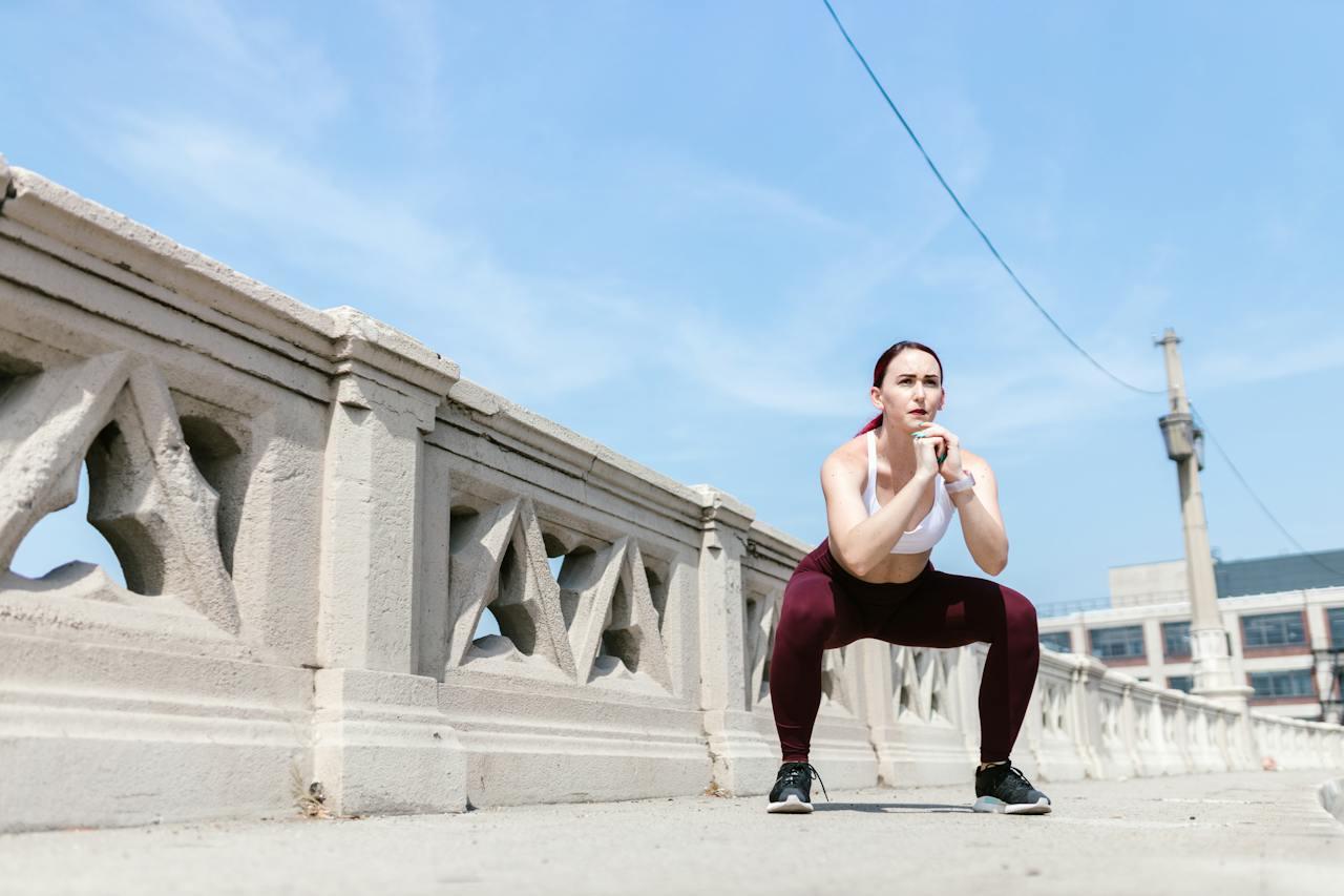 Mujer haciendo sentadillas en la vereda.