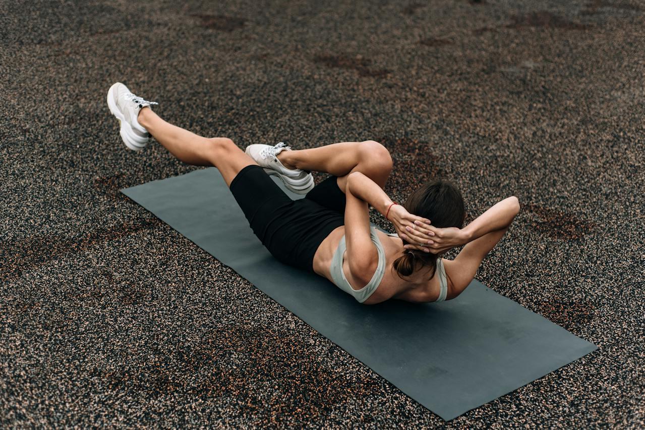 Mujer recostada en el piso haciendo ejercicio abdominales. 
