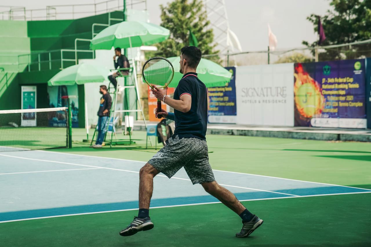 Hombre de espalda sobre una cancha de tenis. 