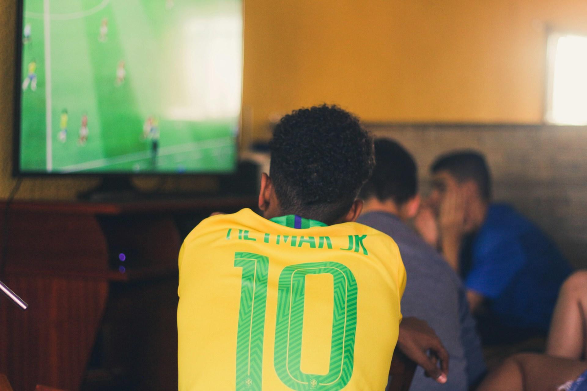 Chico con la camiseta de futbol de brasil viendo un partido.