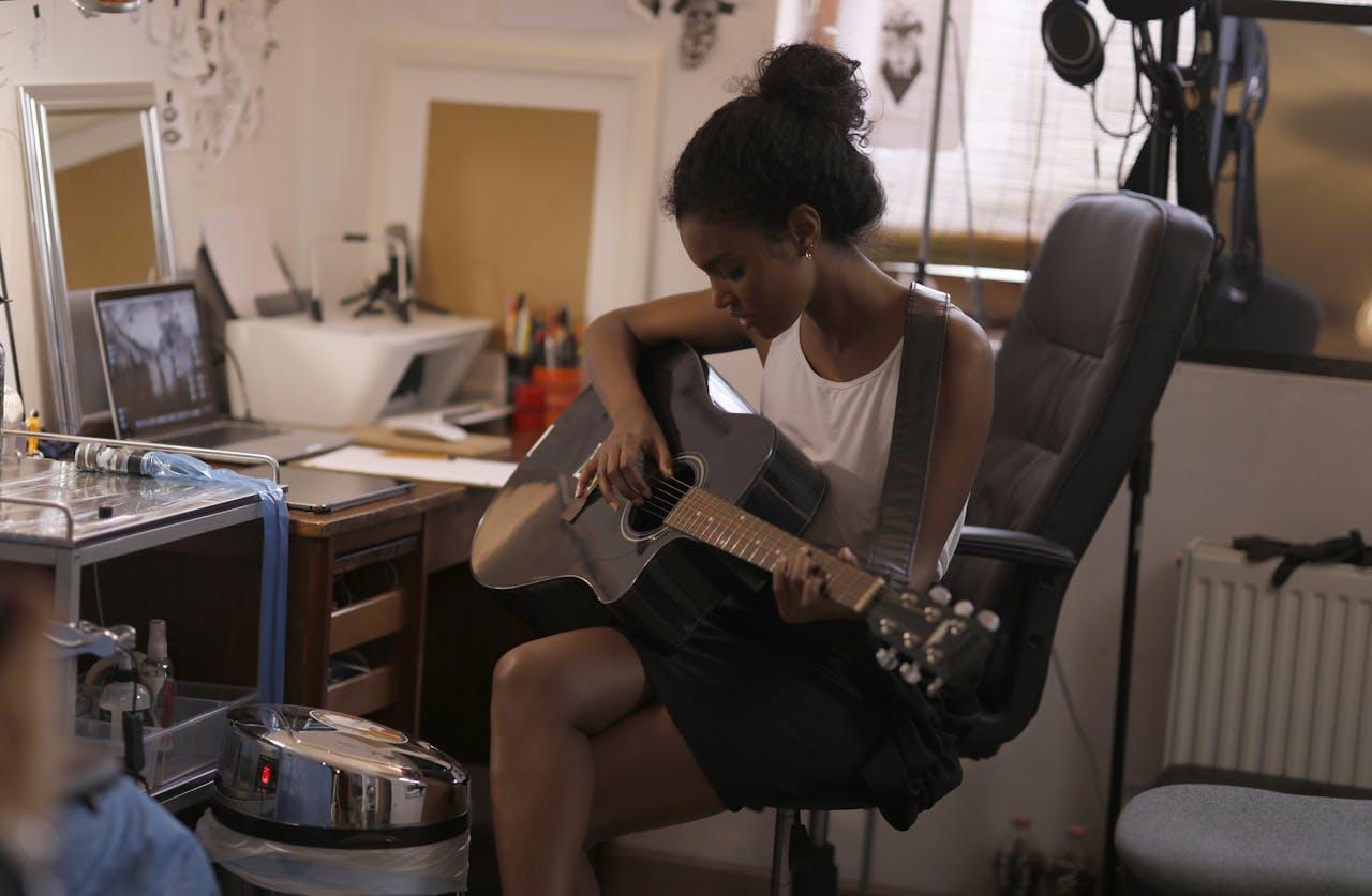 Mujer sentada en la habitación con una guitarra.