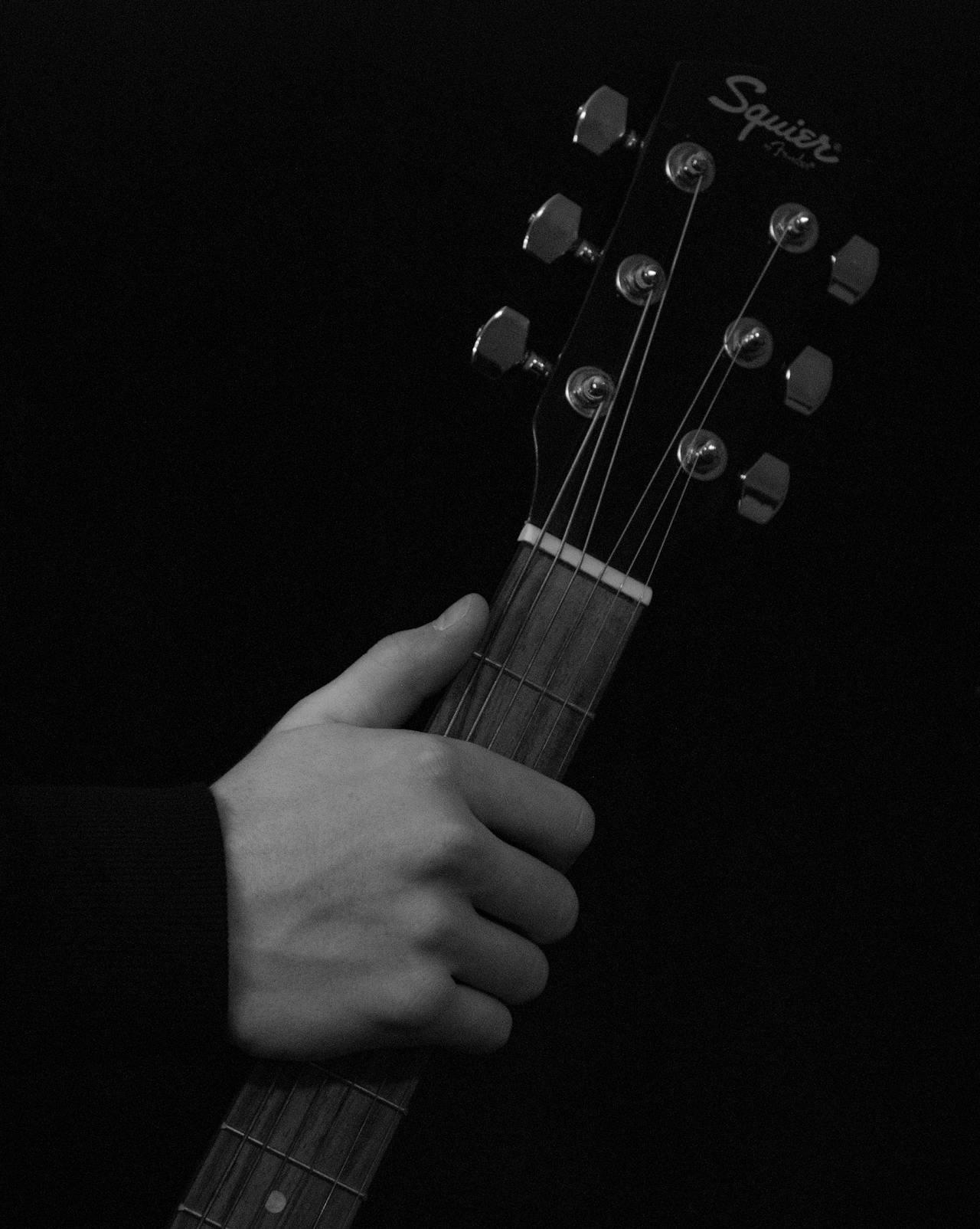 Mano de persona sosteniendo una guitarra.